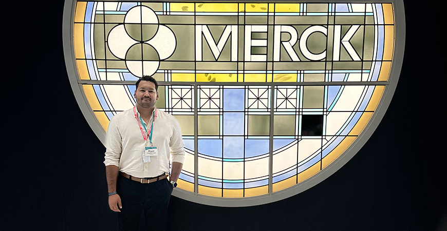 male with brown hair standing in front of a Merck graphic